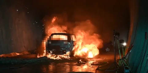 Ein brennendes (zensiertes) Auto steht in einem dunklen Tunnel.